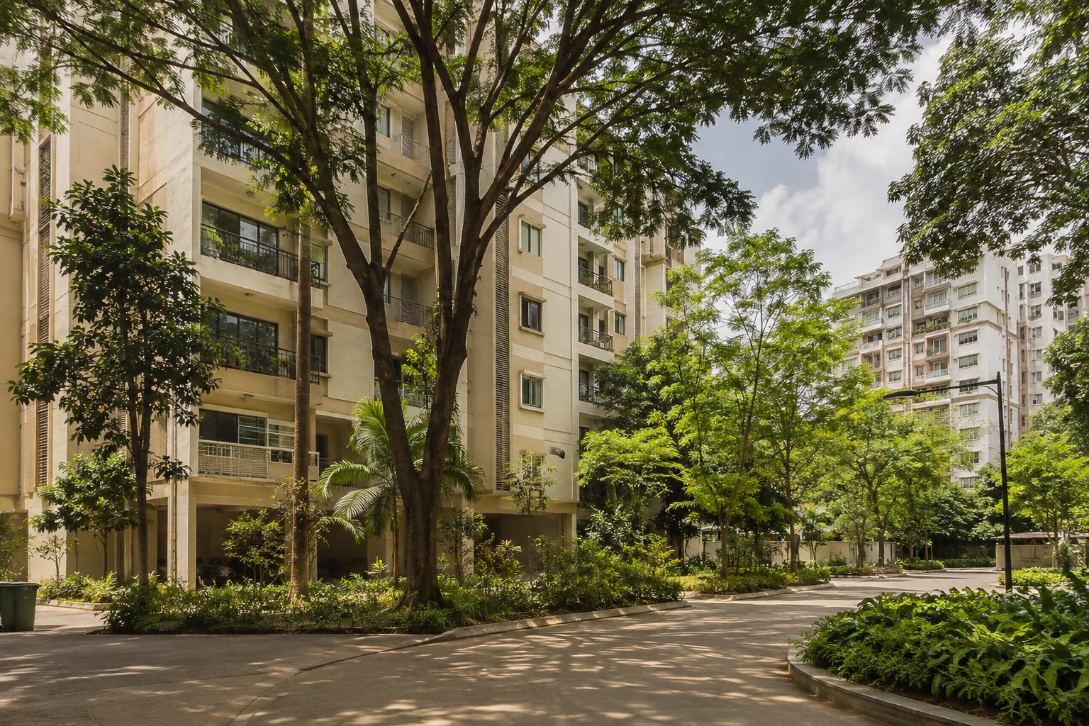 Begrünte indische Apartmentanlage mit mehreren Wohngebäuden und schattigem Innenhof
